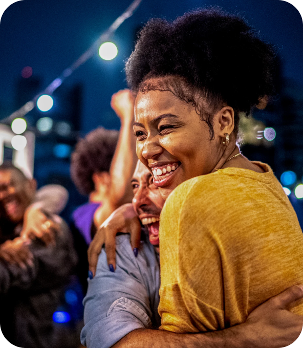 Two friends celebrating together outdoors at night, embracing and smiling, capturing a joyful moment of connection and freedom.