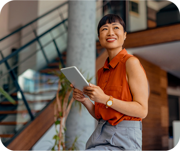 Smiling woman holding a tablet and looking upward, capturing a sense of progress, optimism, and personal momentum