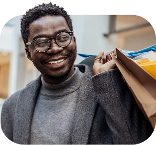 Smiling man holding shopping bags and a smartphone in a mall, representing confidence and ease