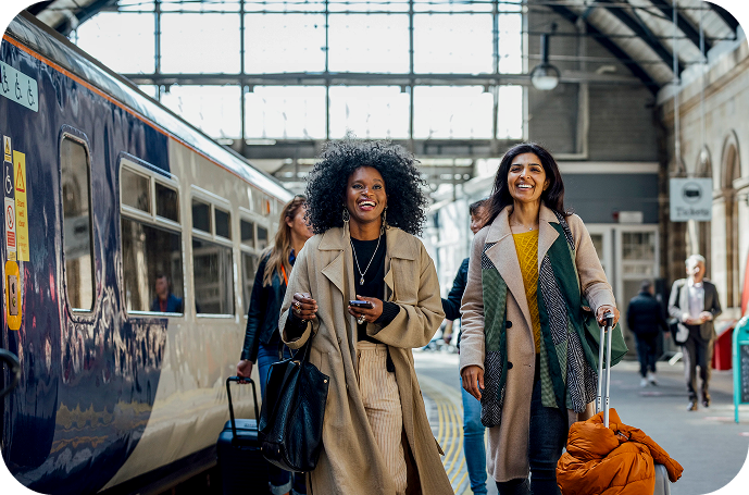Two women walking through a train station with luggage, capturing the ease of international travel.